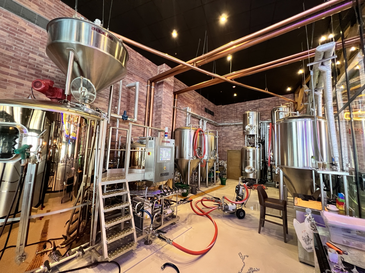 Cervecería industrial con tanques de acero inoxidable y conexiones profesionales